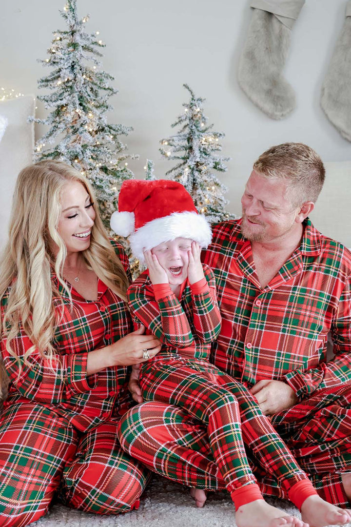 Two children laughing together in matching Caden Lane Christmas bamboo plaid pajamas, showcasing festive holiday family sleepwear in a classic red and green tartan print.