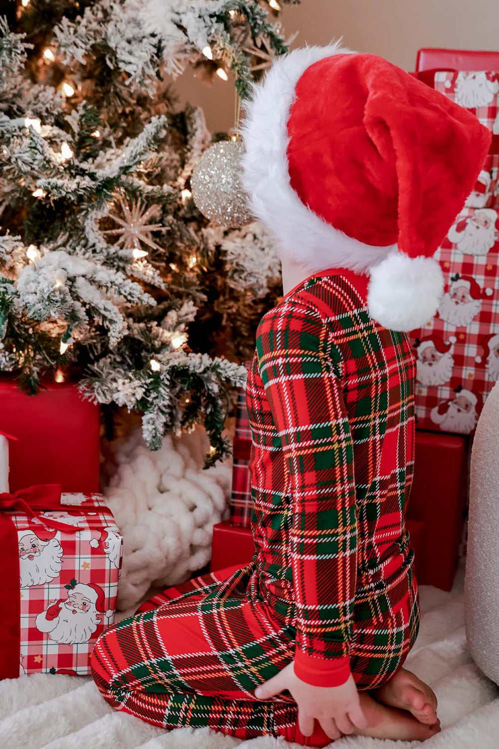 Back view of Caden Lane Christmas bamboo plaid pajamas on a child wearing a Santa hat, showcasing the festive red and green tartan print perfect for matching family Christmas pajamas.