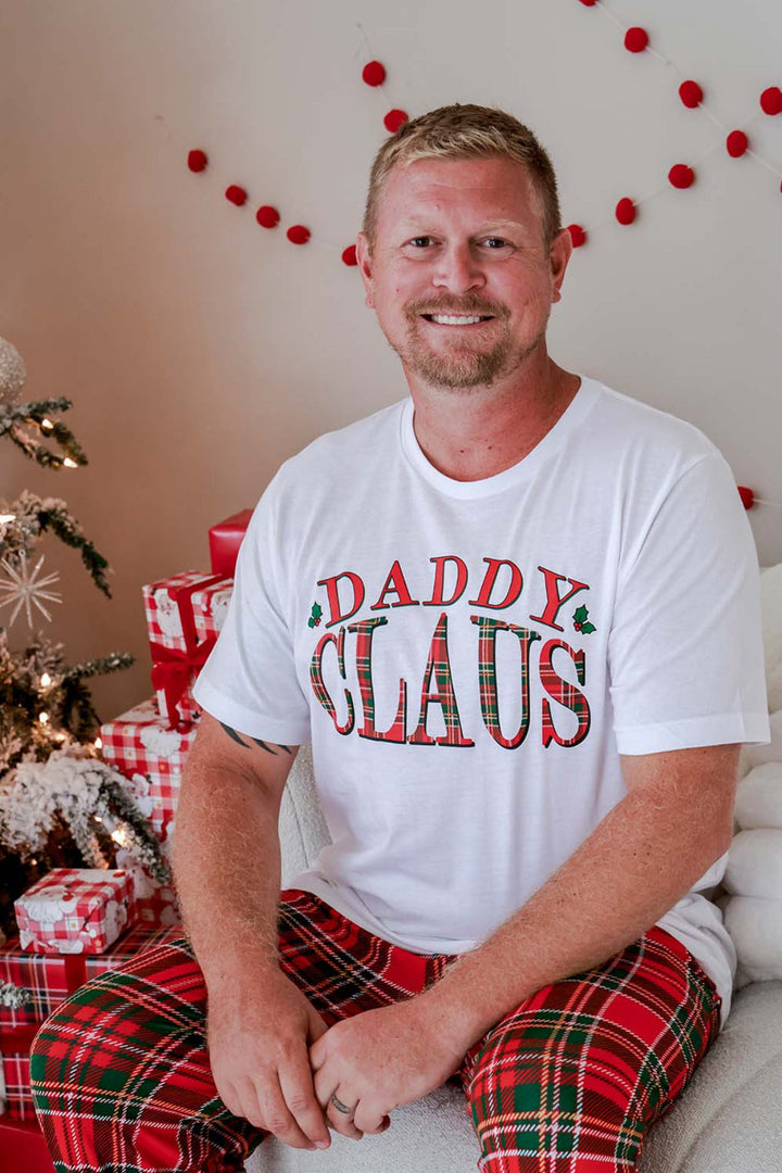 Caden Lane Daddy Claus Christmas graphic tee for dads styled with matching red plaid family Christmas pajama pants, perfect for festive holiday photos, Christmas morning, and coordinating family pajamas.
