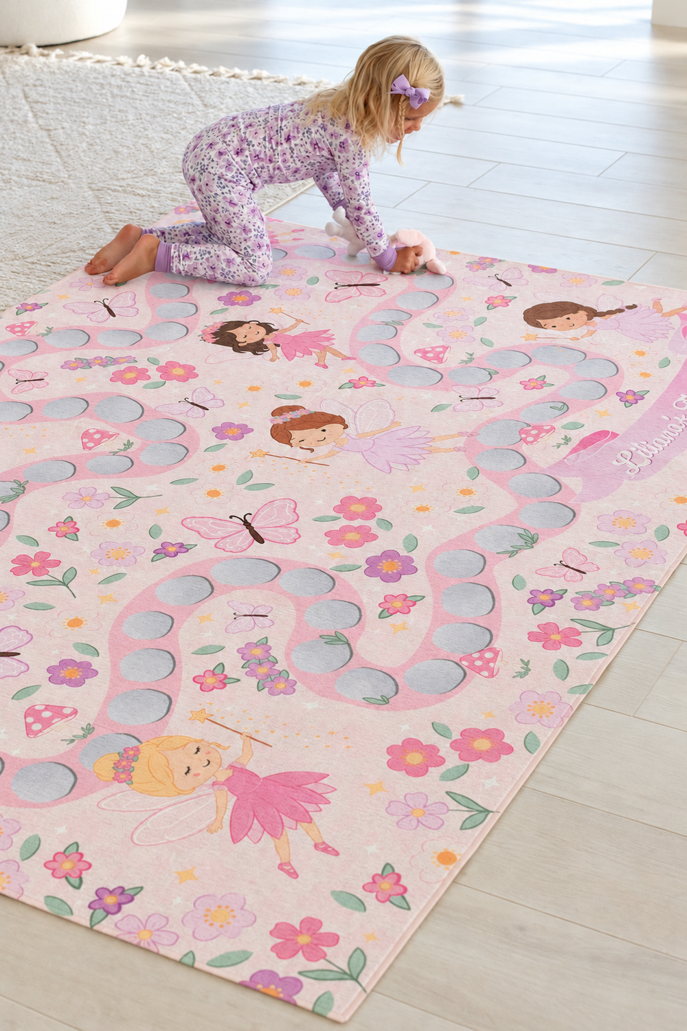 Girl crawling across a personalized Caden Lane fairy garden playroom rug featuring colorful fairies, flowers, butterflies and mushrooms.