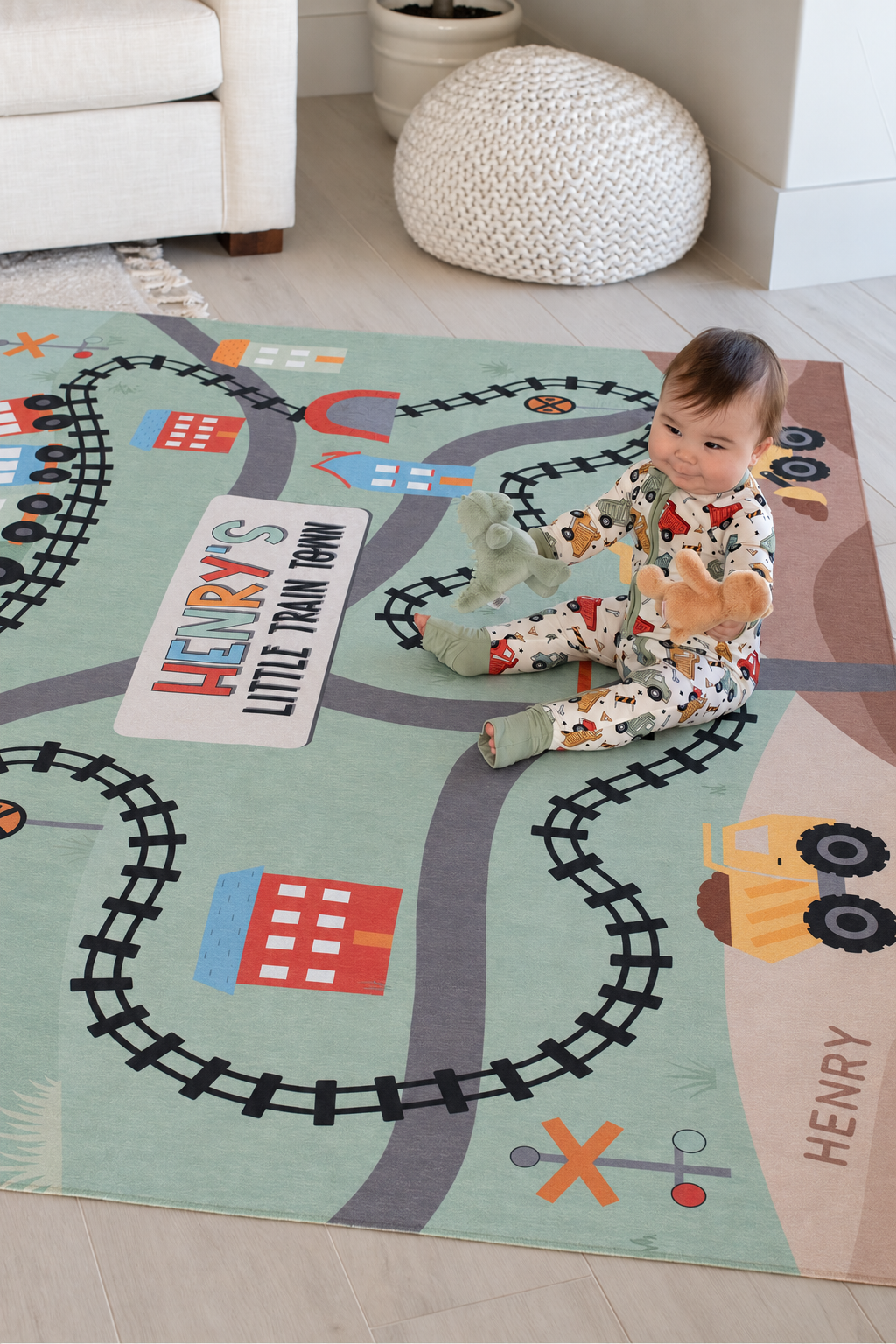 Baby crawling on a personalized Caden Lane train playroom rug featuring colorful railroad tracks, roads and construction vehicles.