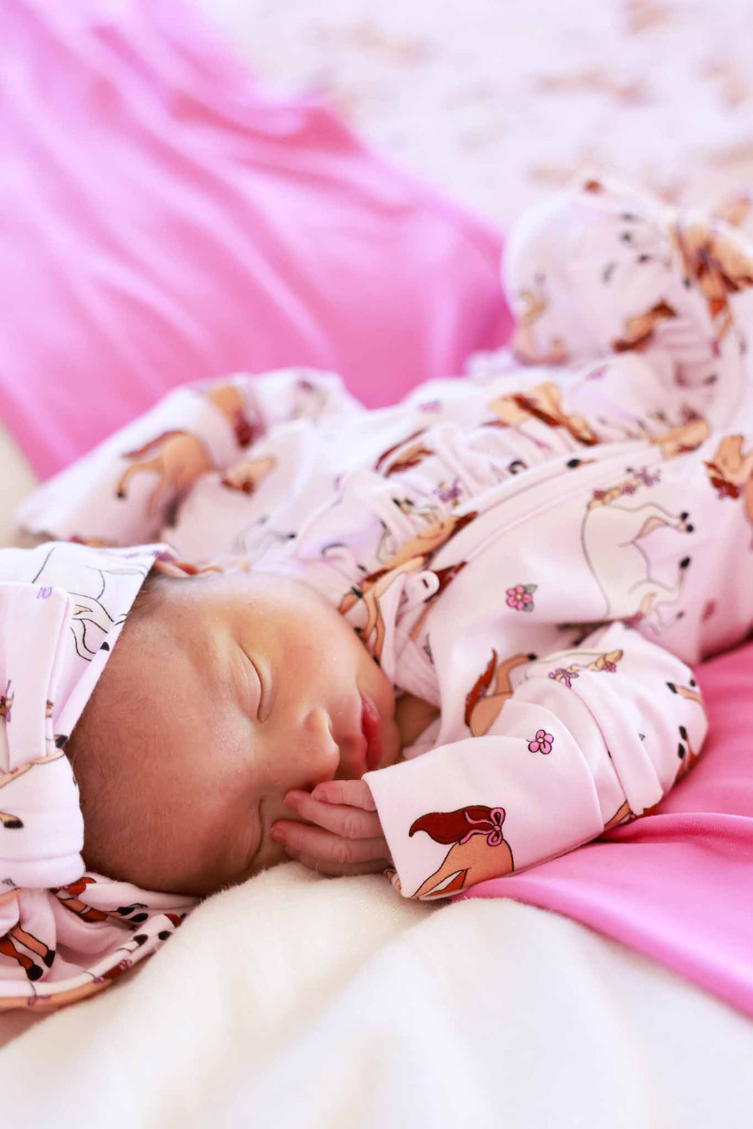 baby girl wearing pink pony club ruffle zipper footie and headwrap