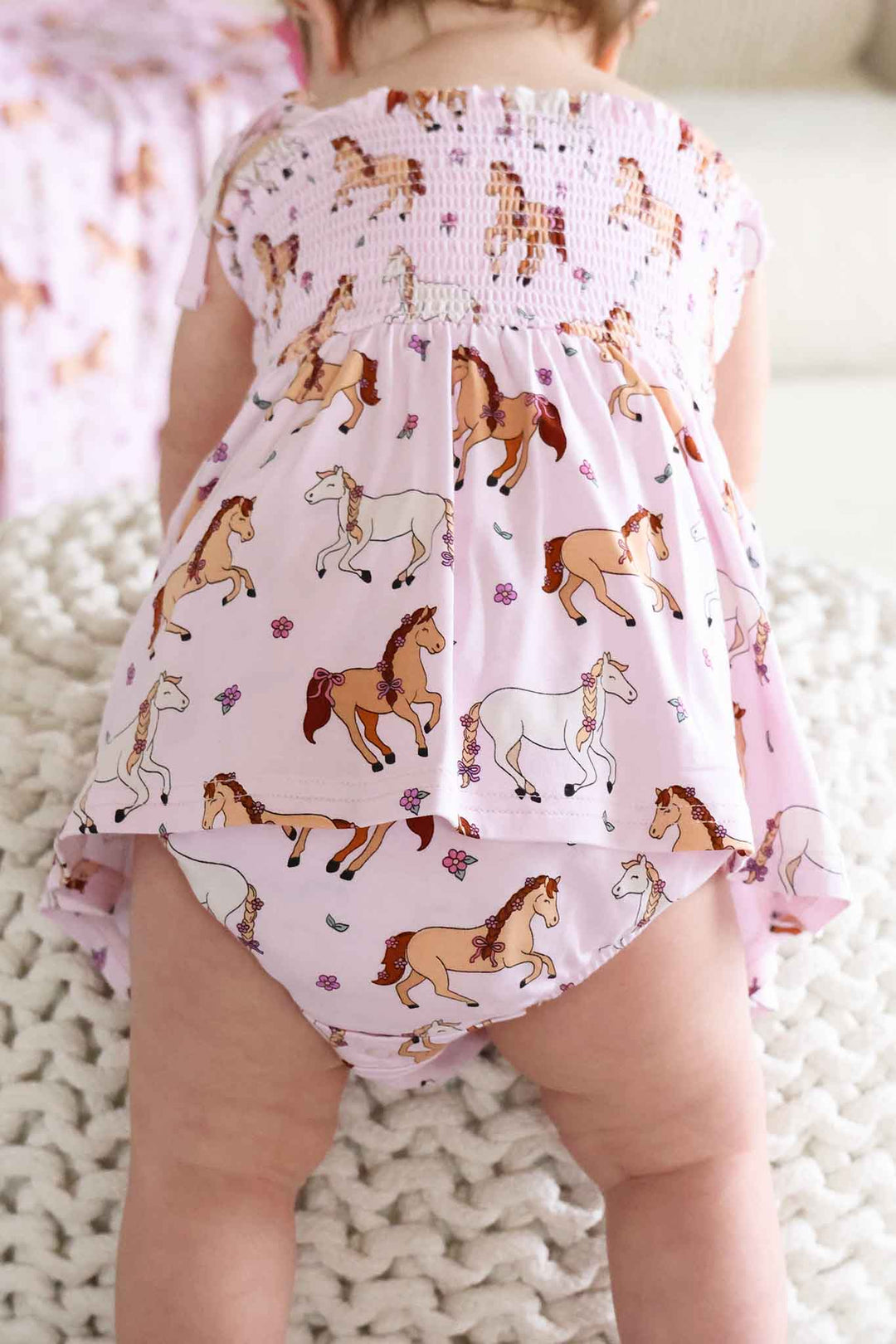 back view of smocked skirt bodysuit for baby girls in girly horse print 