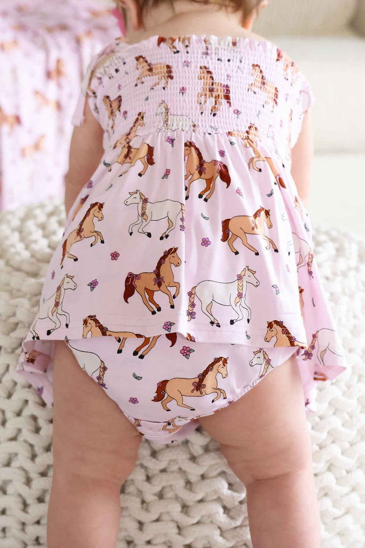 back view of smocked skirt bodysuit for baby girls in girly horse print 