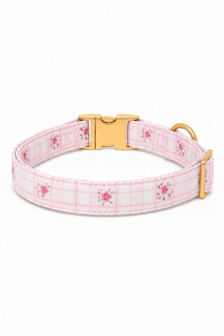 A Lane & Leash light pink and white plaid dog collar with small pink floral motifs, featuring a gold-tone quick-release buckle and a gold-tone D-ring, shown on a plain white background.