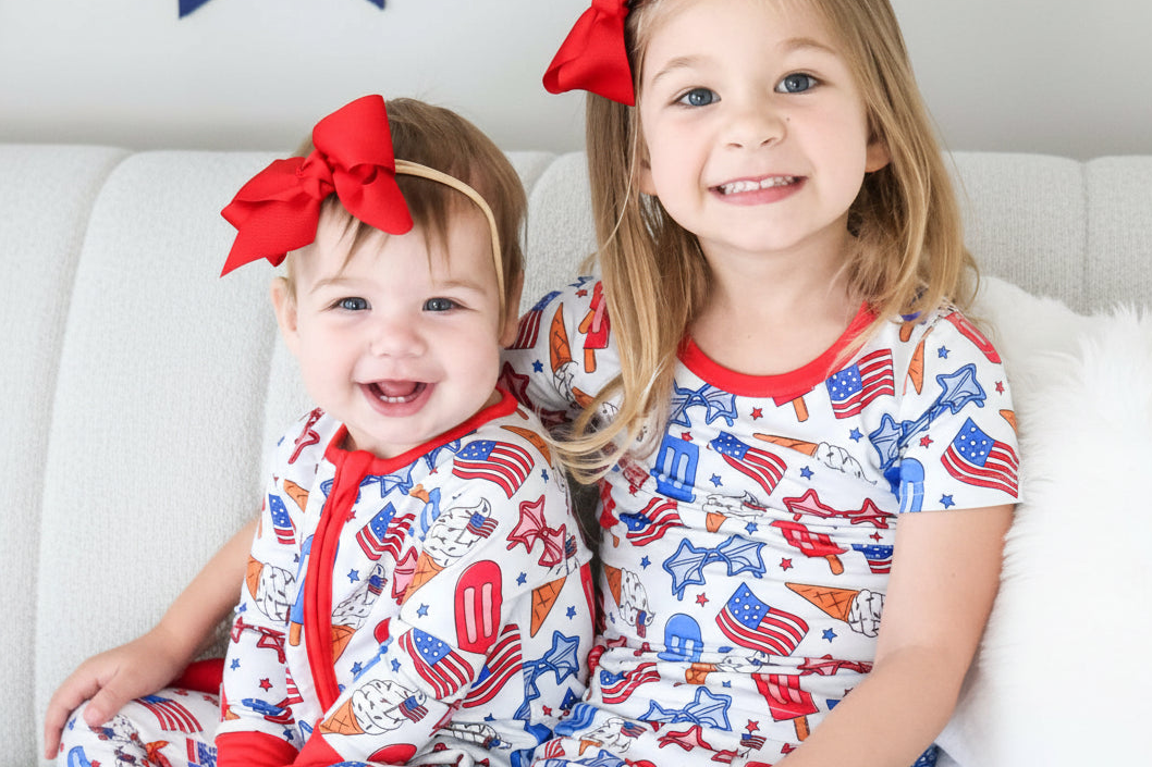 Baby and sister wearing matching Red, White & Cool zippered romper and two piece pajama sets! 