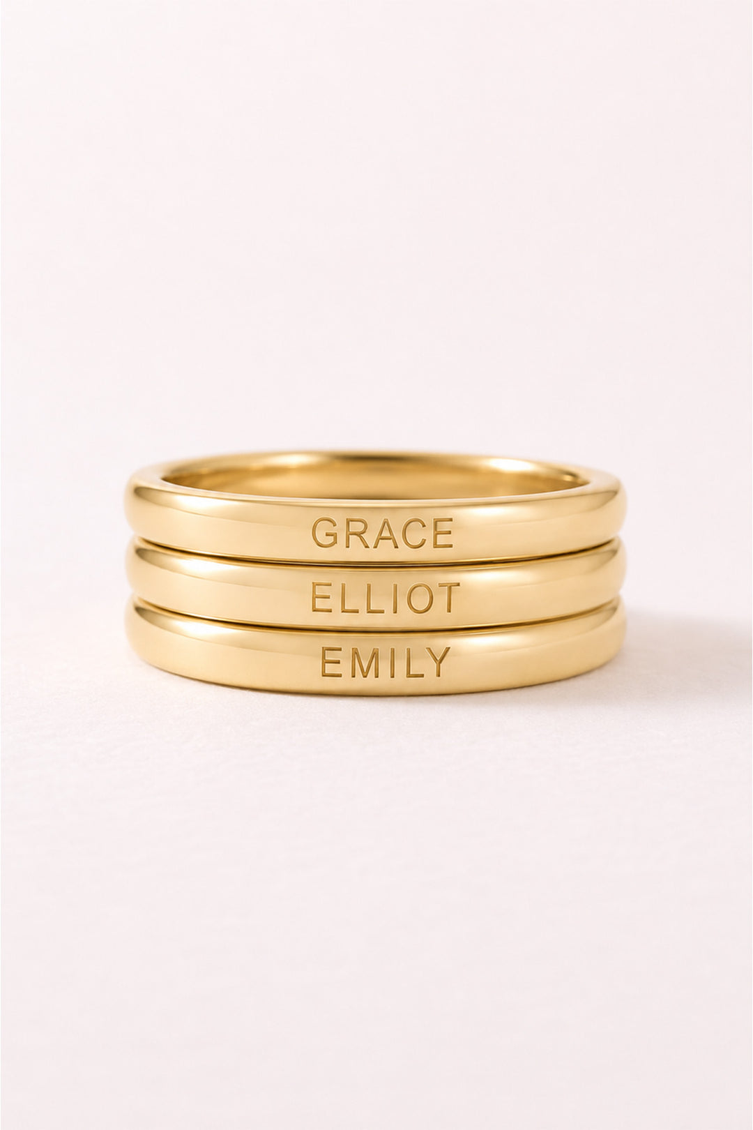 Caden Lane personalized gold ring stacked three times and engraved with the names Grace, Elliot, and Emily.