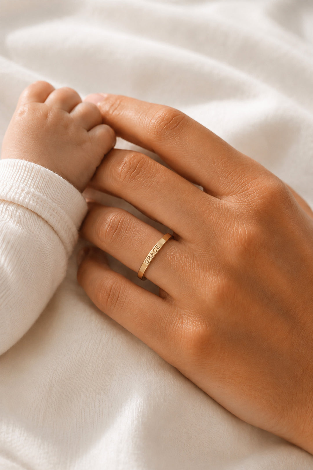 Caden Lane personalized gold name ring engraved with Grace worn by a mother while holding her baby's hand.