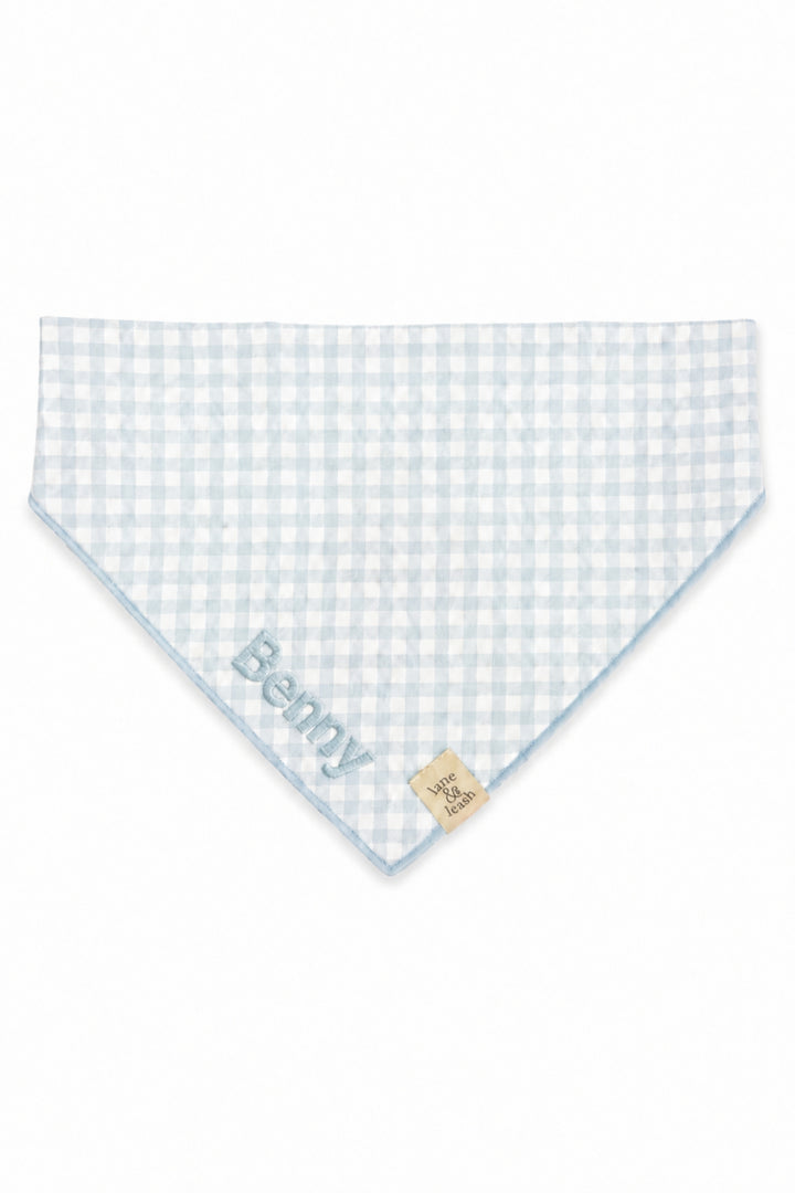A Lane & Leash light blue and white gingham checkered pet bandana with the name 'Benny' embroidered in blue on one corner and a small beige brand tag on the opposite side, shown on a plain white background.