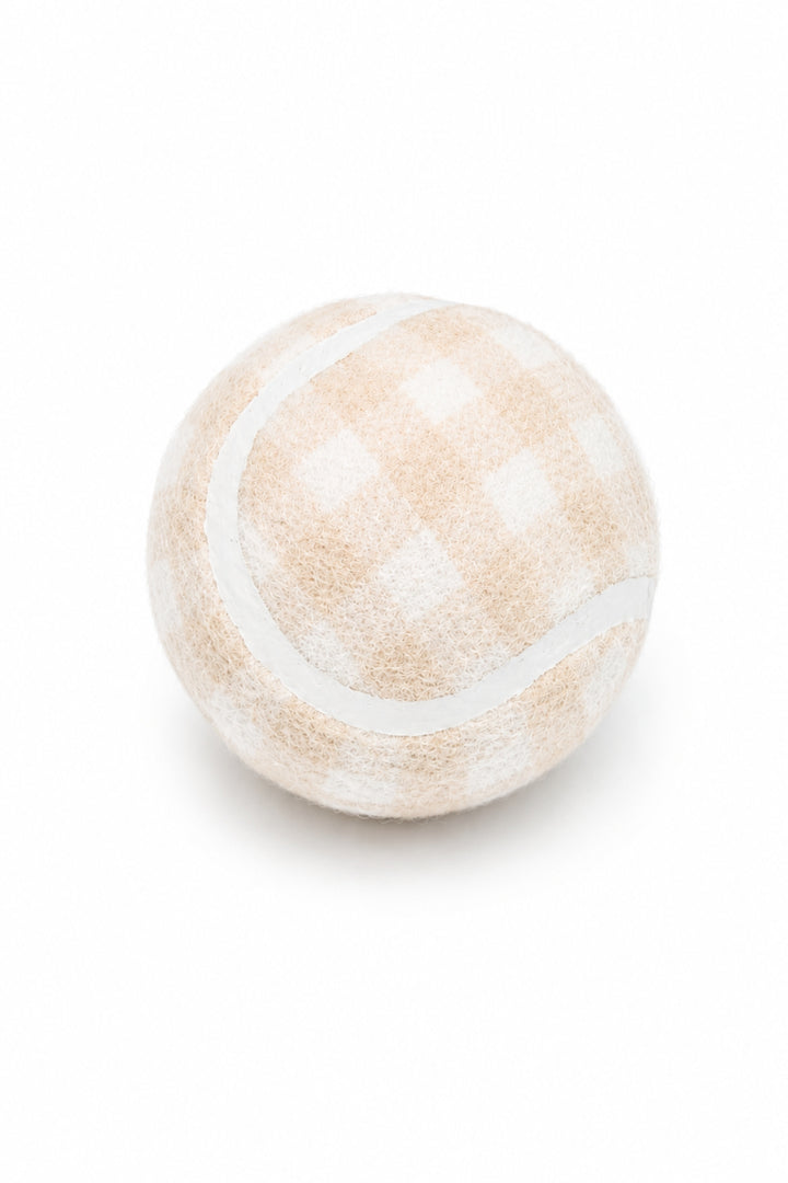 A Lane & Leash dog tennis ball, featuring a soft beige and white gingham checkered pattern with a white curved stripe, isolated on a white background.