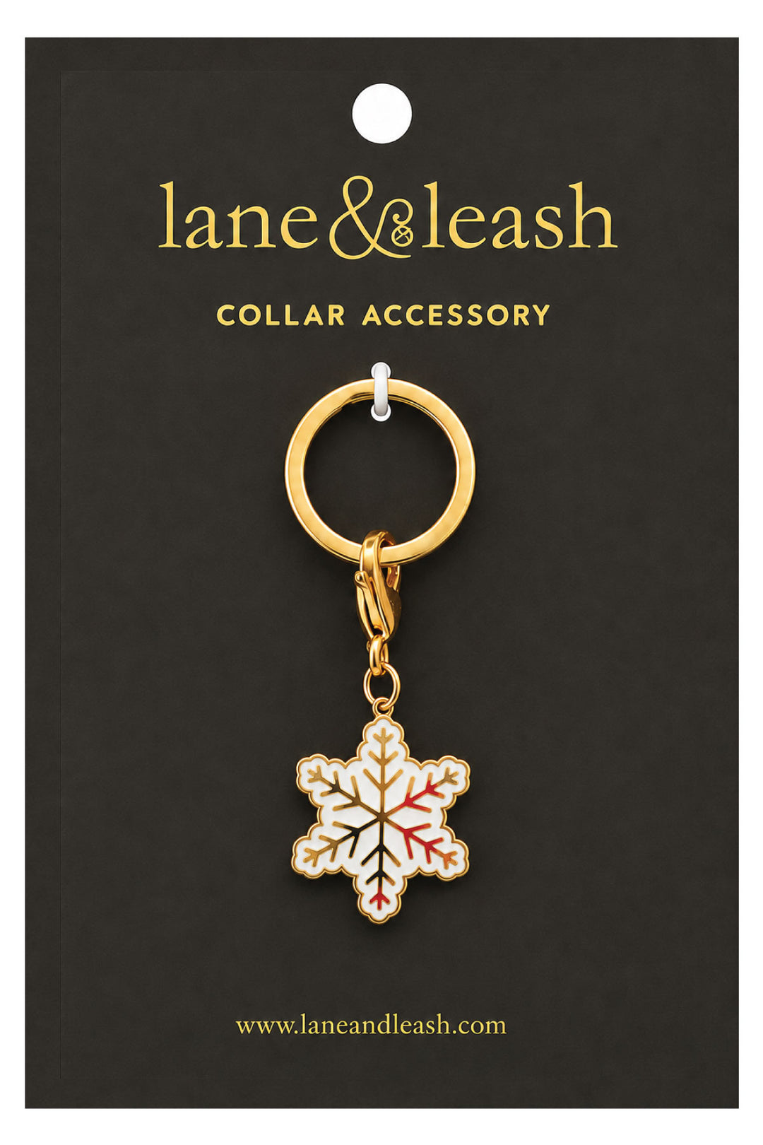 Lane & Leash snowflake charm collar accessory on branded packaging card, gold ring with lobster clasp and white enamel snowflake charm with gold and red accents