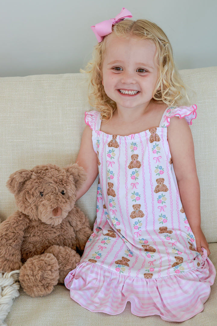Young girl sitting with teddy bear smiling wearing Full Length Ruffle Nightgown in Beary Lovely print, front view showing pink ruffle hem