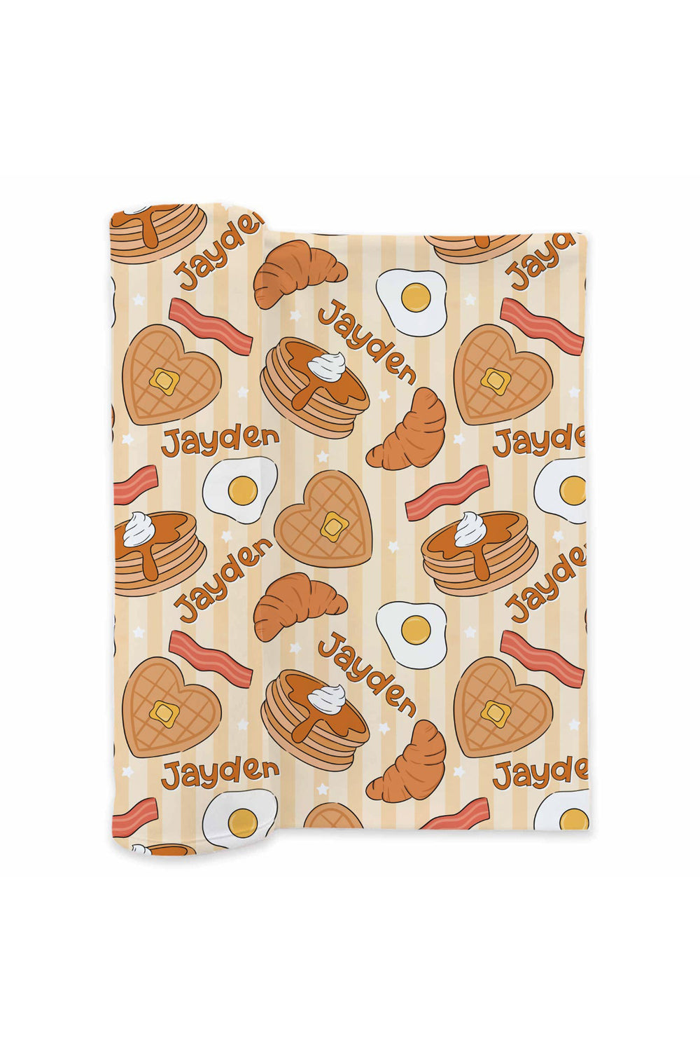 A folded Caden Lane swaddle featuring a repeating breakfast-themed pattern with pancakes, croissants, bacon, eggs, and the name 'Jayden' on a light beige background.