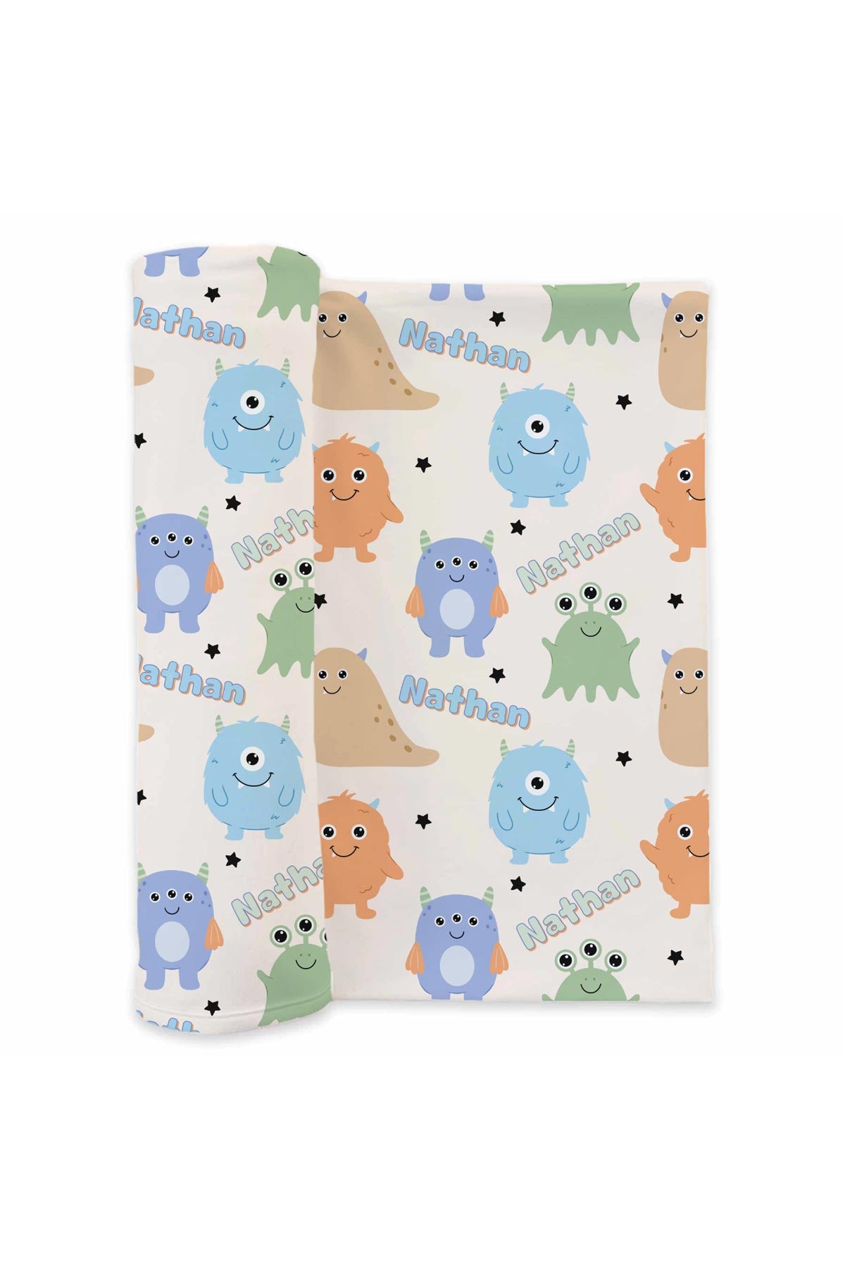 Product shot of Caden Lane personalized "Nathan" swaddle blanket rolled out, showing Little Monsters print with blue, purple, orange, tan, and green cartoon monsters and stars on a cream background