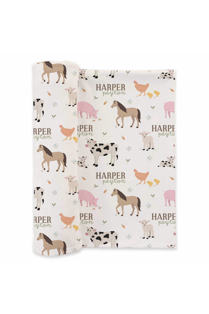 Caden Lane personalized farm animal swaddle blanket flat lay with custom name 'Harper Peyton' and cow, horse, pig, chicken, and lamb print