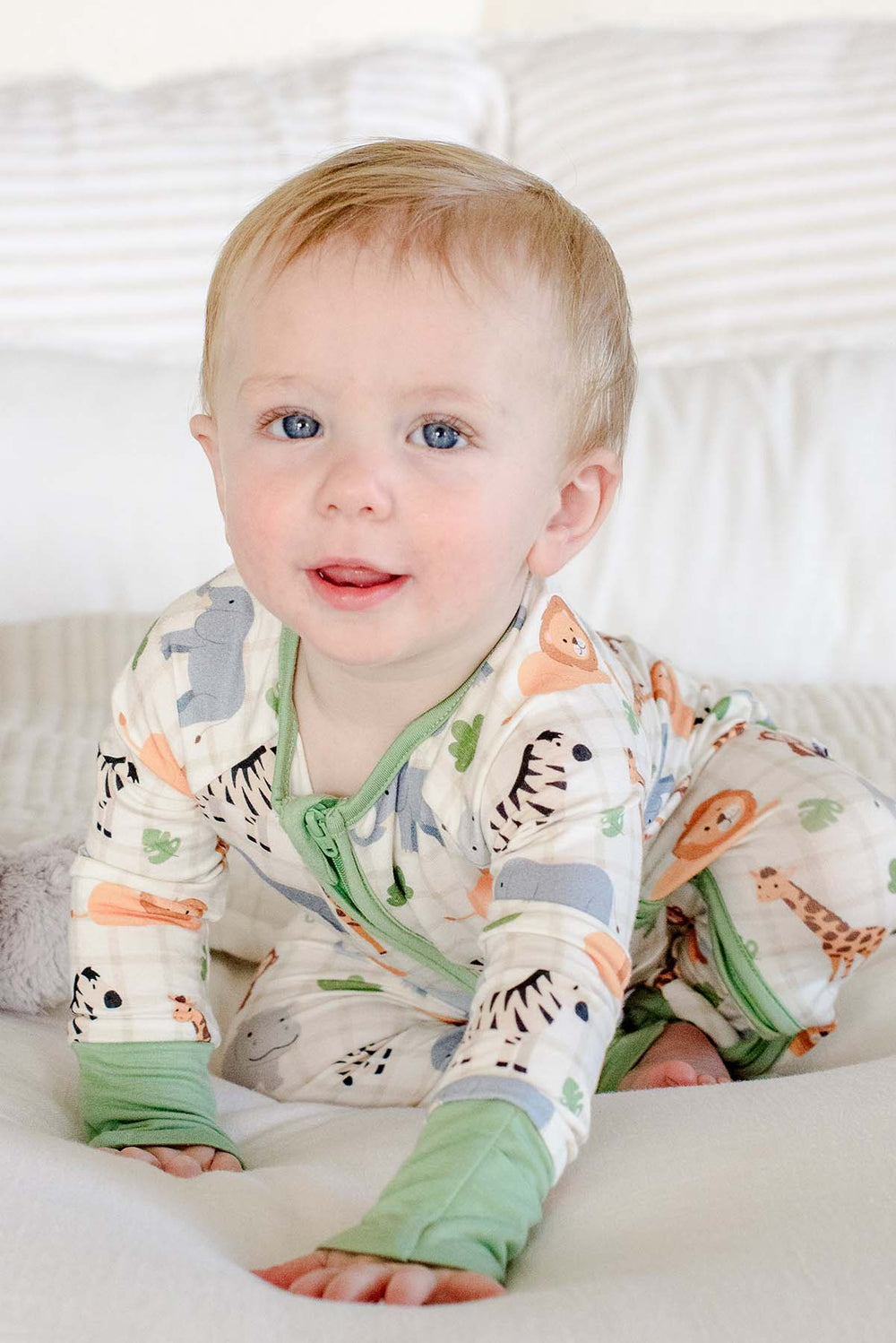 Smiling baby boy crawling across a bed in a Caden Lane Wild Child convertible zip romper with a sage green zipper and cuffs.