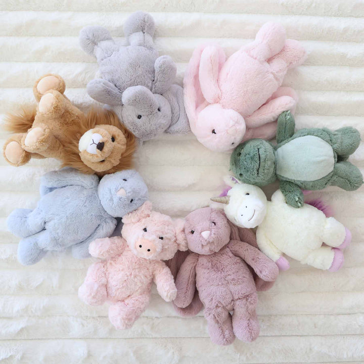 lion, elephant, pink bunny, dinosaur, unicorn, purple bunny, pink big and blue bunny stuffed animals laying in a circle 