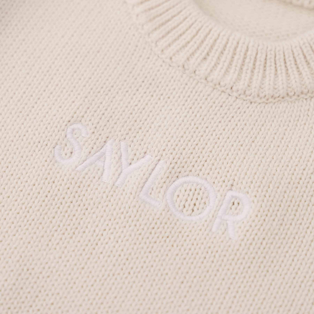 ash knit embroidered long sleeve sweater romper for babies with white thread in block font 