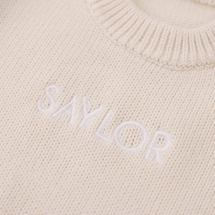 ash knit embroidered long sleeve sweater romper for babies with white thread in block font 