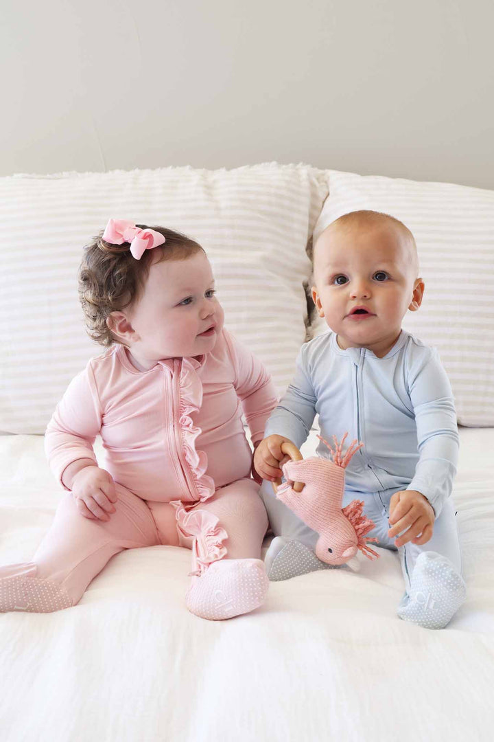 two babies sitting next to each other in pastel footies blue and pink 