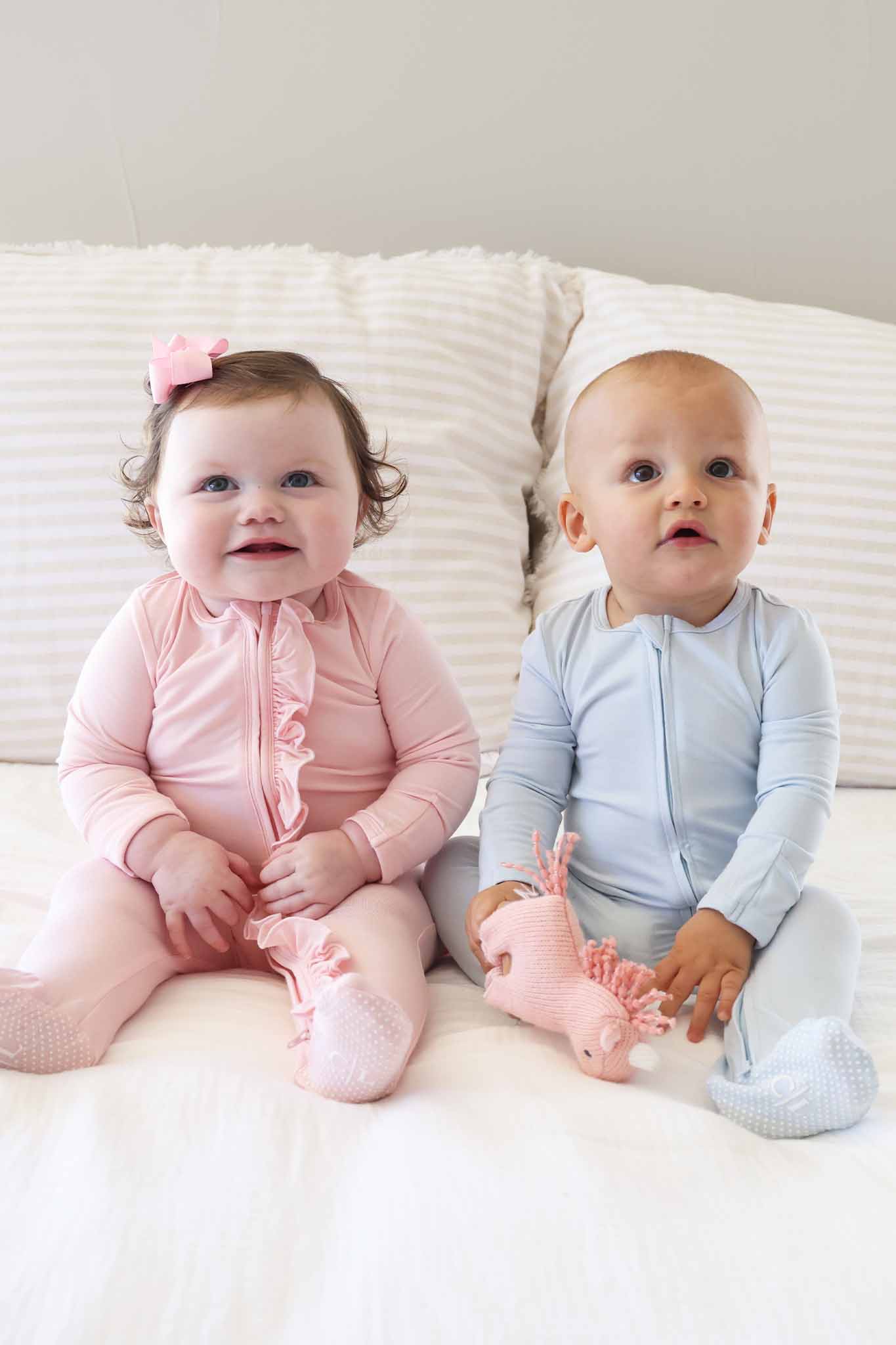 two sitting babies in pastel blue and pink footies