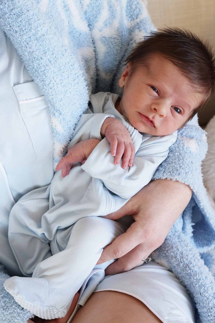 baby boy laying in mom's arms wearing matching lights blue outfits 