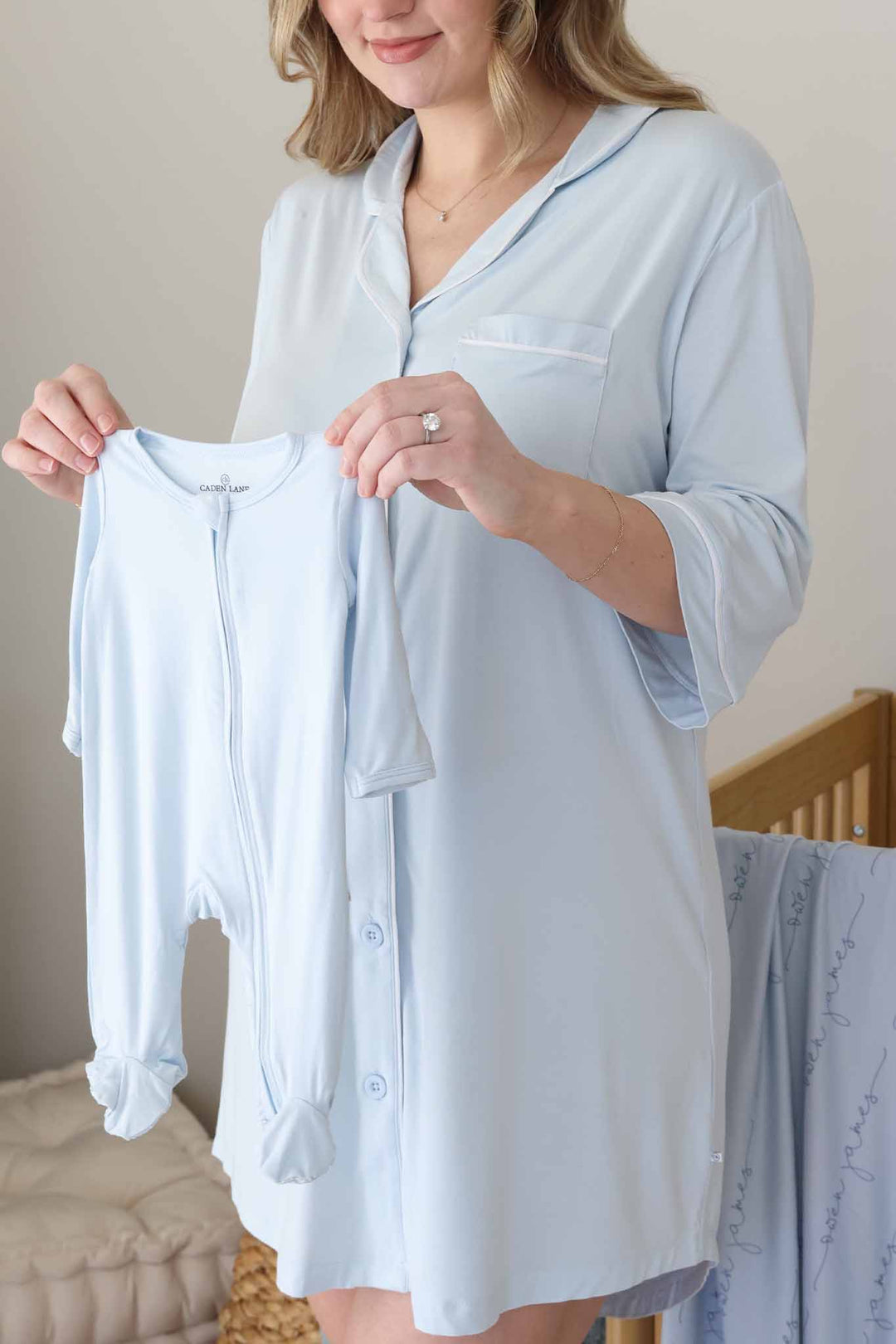 mom in baby blue labor & delivery gown holding up a matching footie 