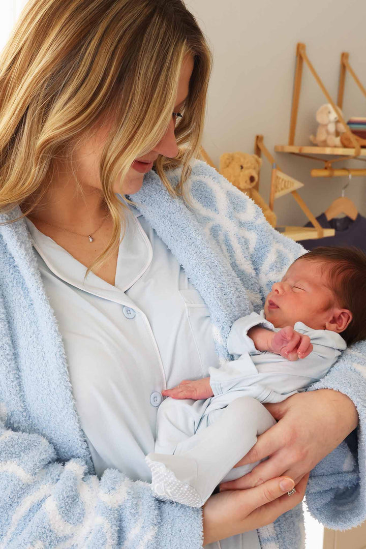 mom holding baby wearing matching light blue outfits 