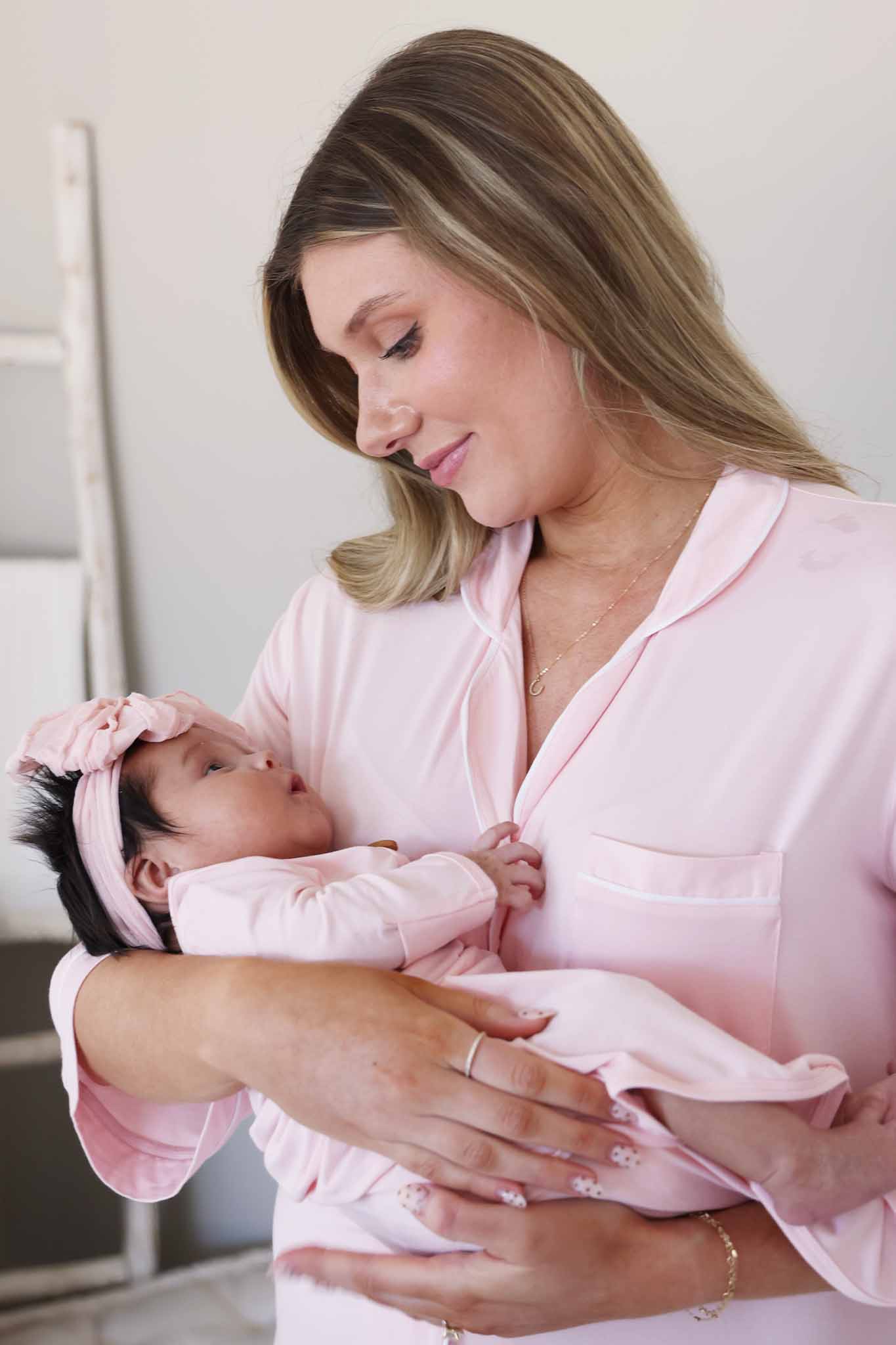 mom looking down at baby in matching baby pink gowns 