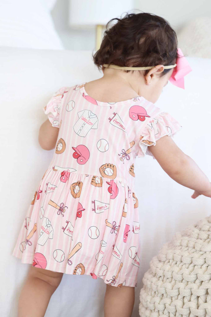 walking baby girl in baseball themed bodysuit 