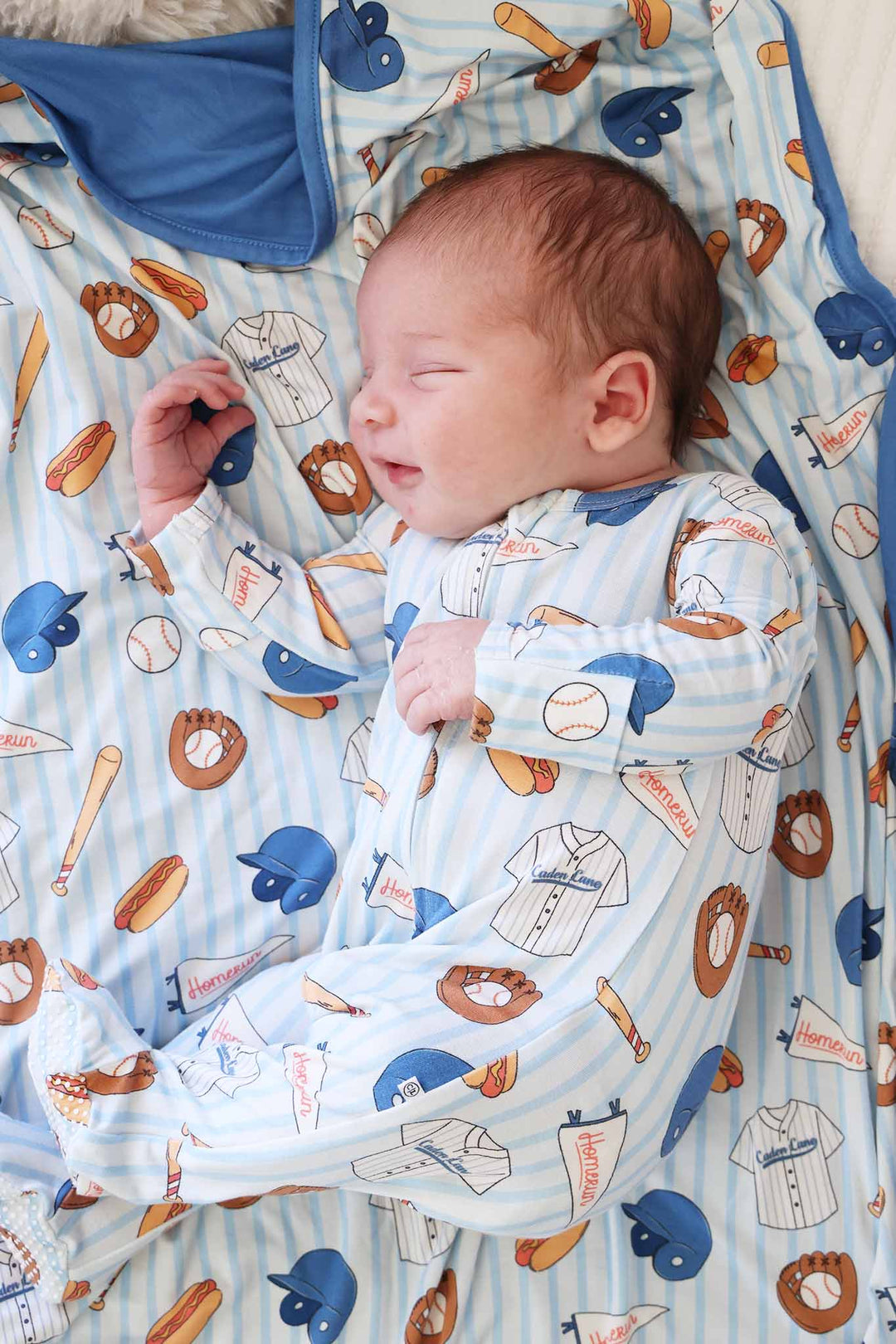 baby boy laying on side in baseball bros footie with matching blanket 