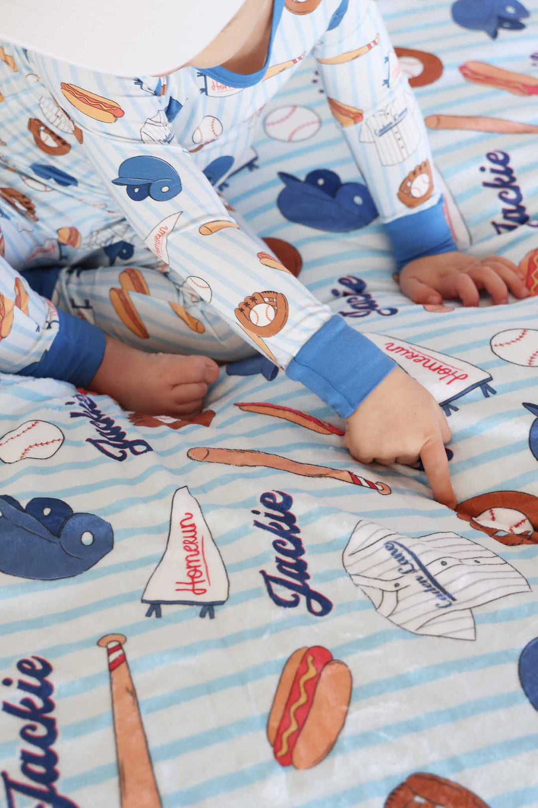boy sitting on blue baseball personalized blanket in matching pajama set 