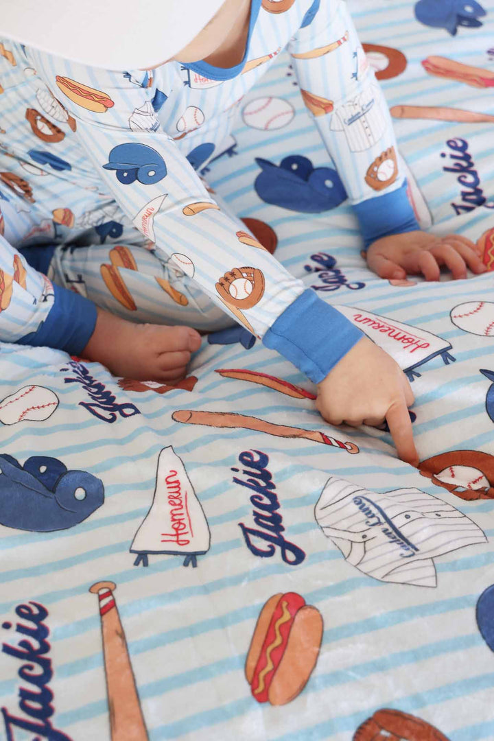 boy sitting on blue baseball personalized blanket in matching pajama set 