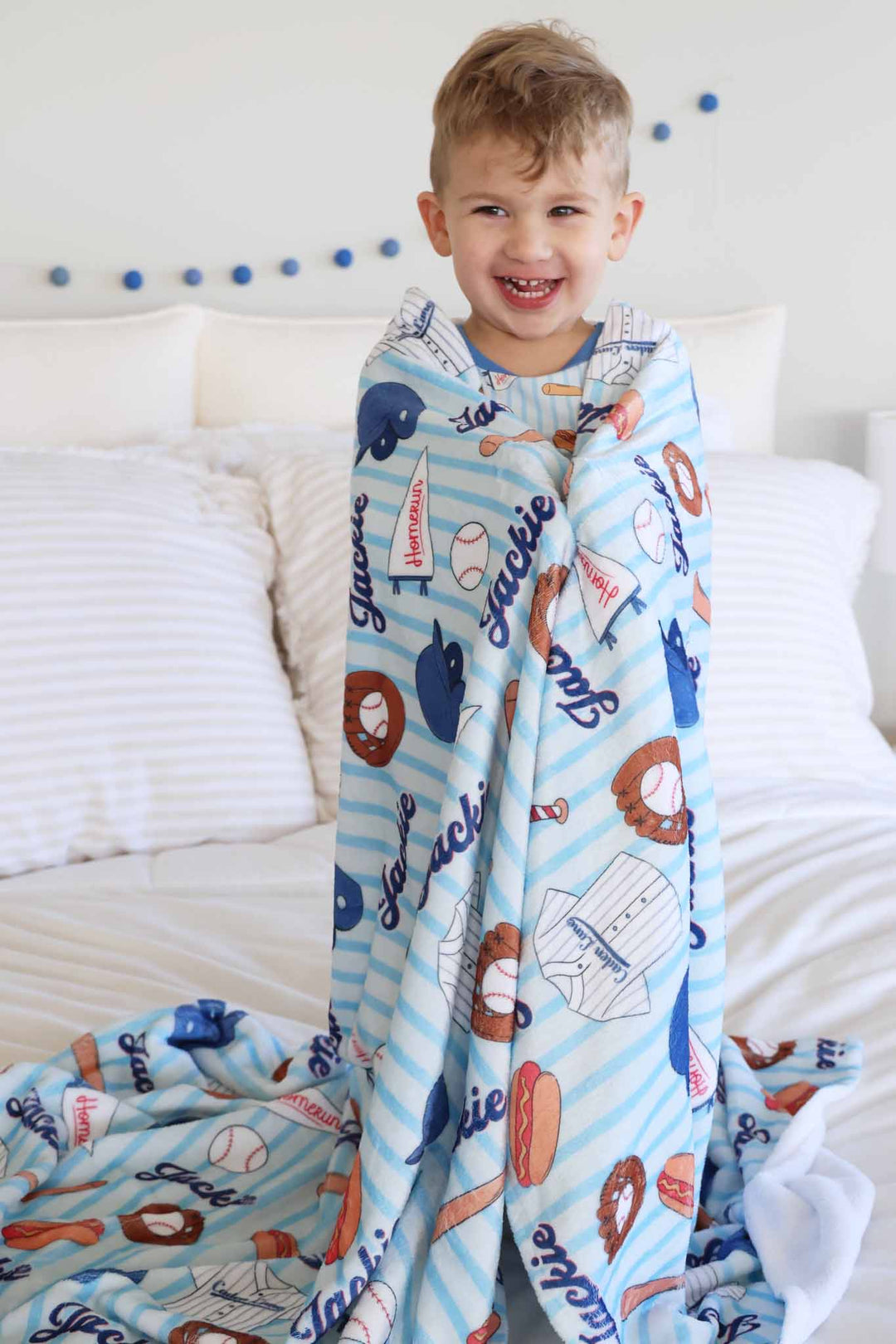 boy wrapped in blue striped baseball themed blanket with sherpa backing 