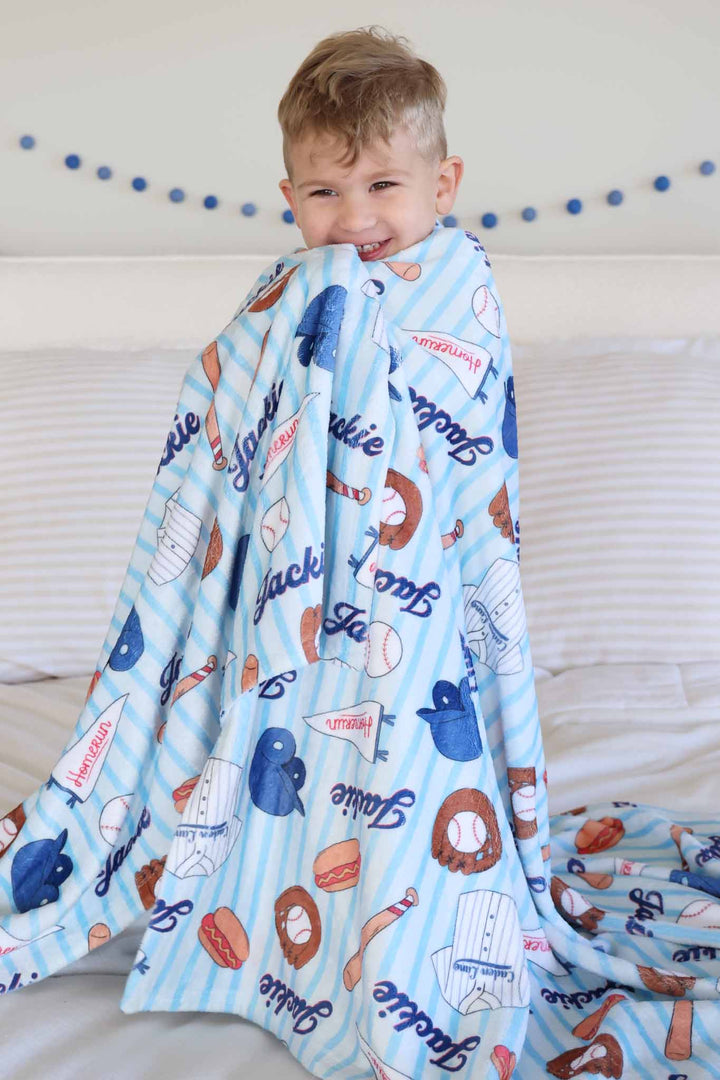 boy wrapped up in blue personalized baseball themed blanket 