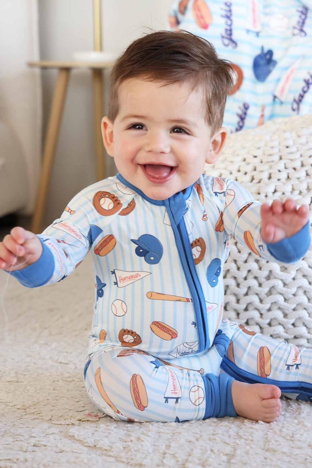 smiling baby boy wearing ballpark bros convertible zip romper pajama with flip mitts and footies 