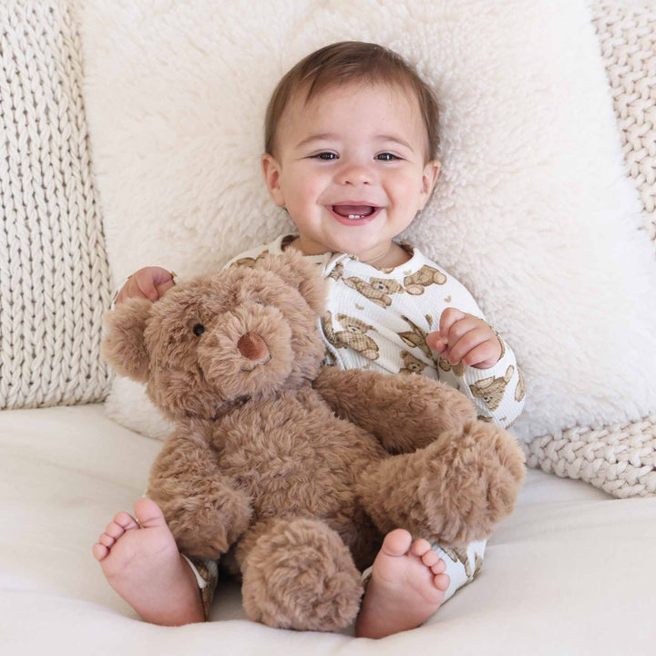 little boy in teddy bear zip romper holding stuffed animal