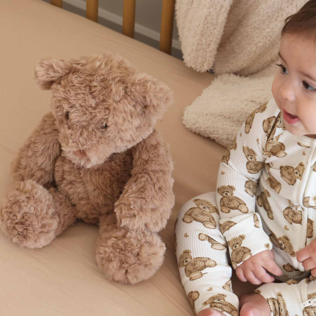 brown fluffy teddy bear stuffed animal for babies sitting in crib