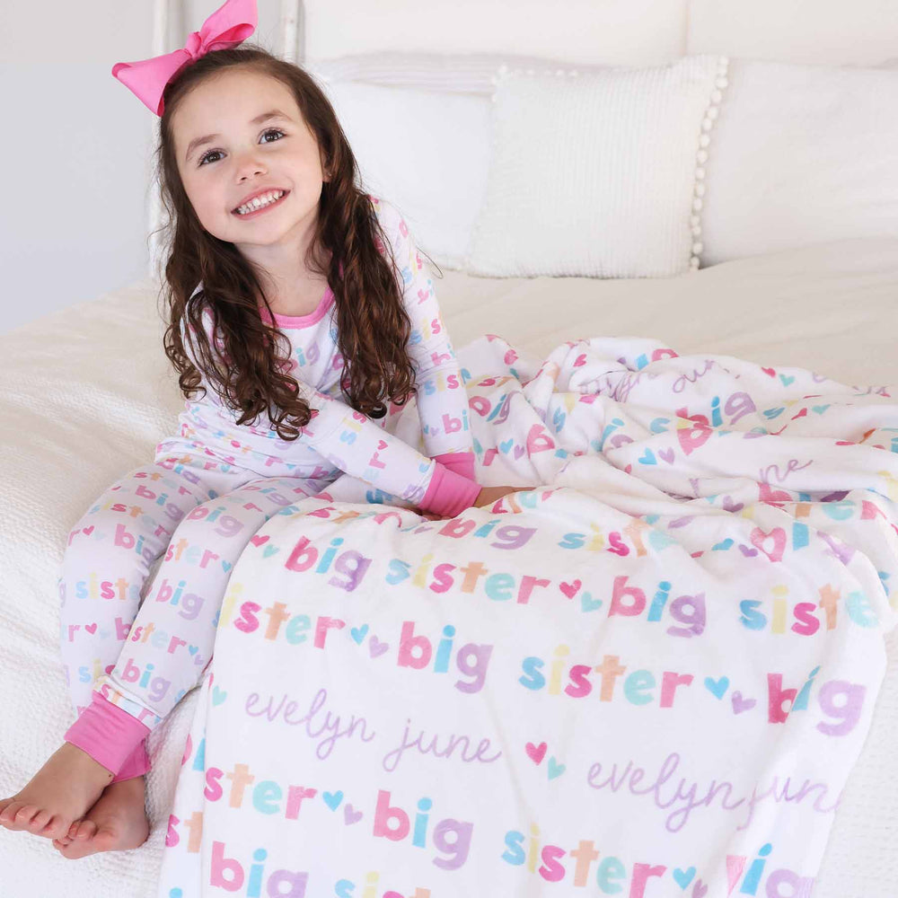 girl with matching big sister personalized kids blanket and pajamas