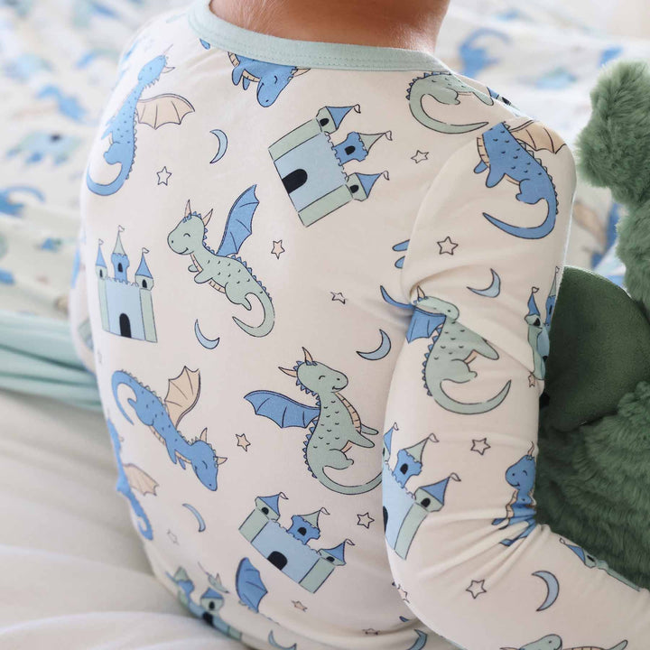 Boy wearing long sleeve pajama set with castles and dragons on cream background