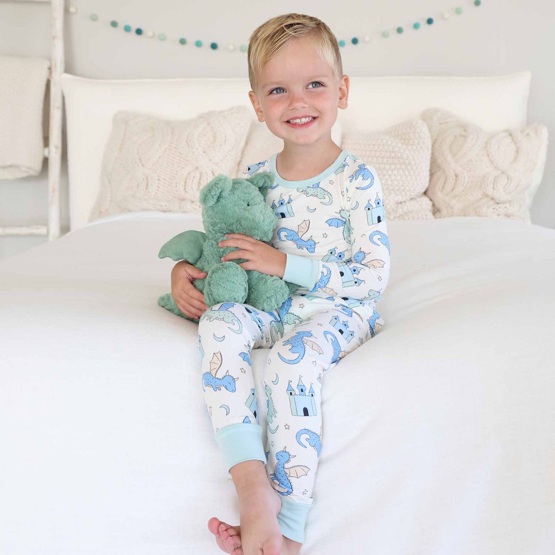 Boy holding stuffed animal while dressed in fantasy-themed pajamas