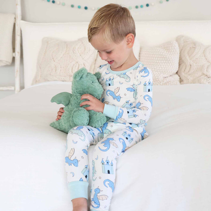Toddler holding plush toy while wearing blue dragon pajamas