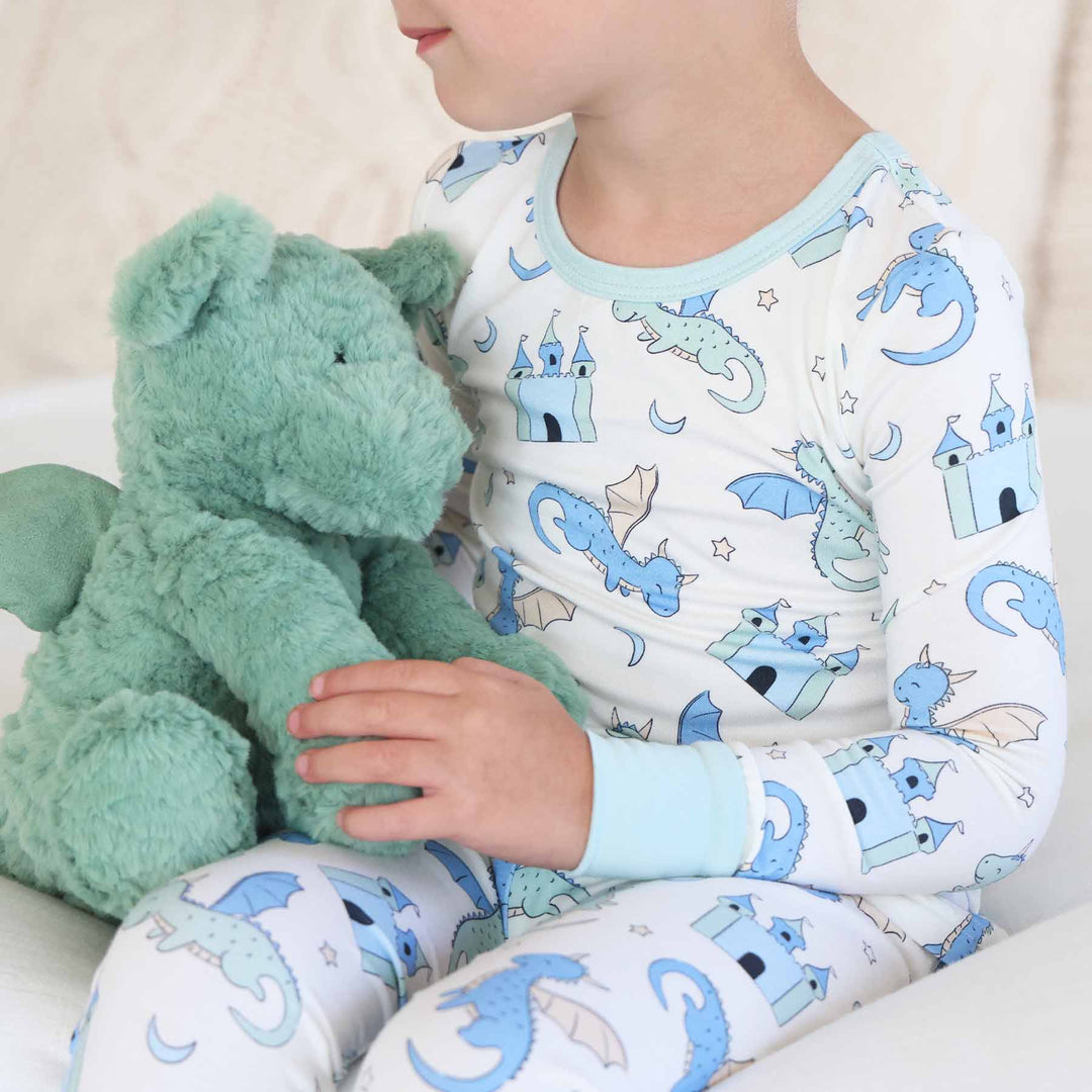 Child in matching pajama top and bottoms decorated with castles and dragons
