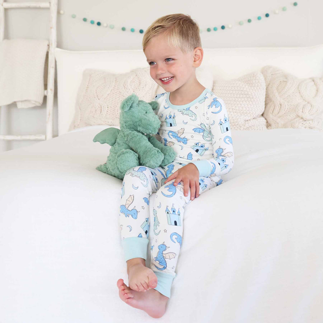 Child holding stuffed toy while wearing whimsical dragon sleepwear