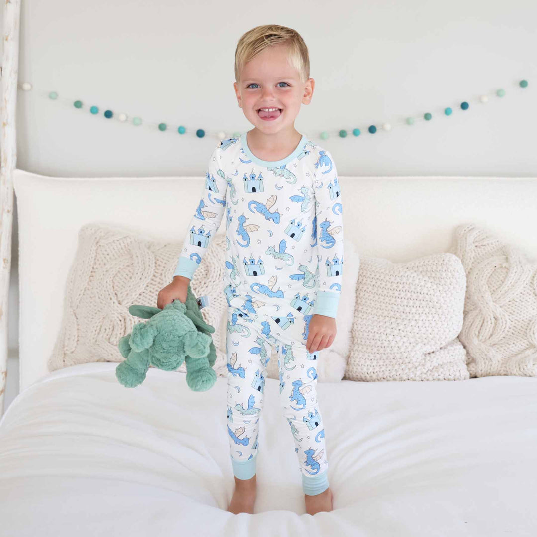 Toddler boy smiling while wearing two piece dragon and castle pajamas