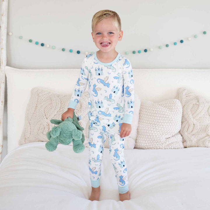 Toddler boy smiling while wearing two piece dragon and castle pajamas