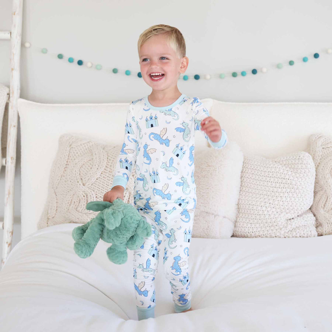 Boy standing barefoot on bed in dragon themed two piece pajamas