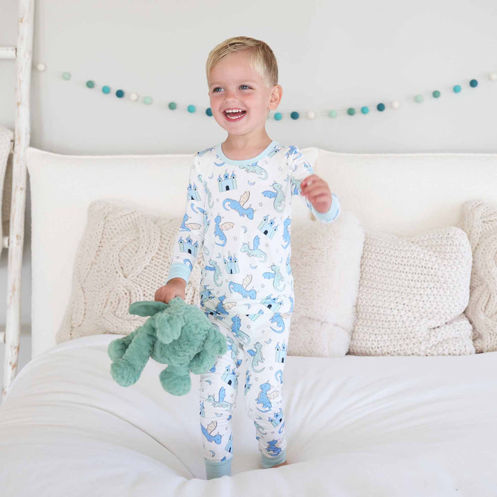 Boy standing barefoot on bed in dragon themed two piece pajamas