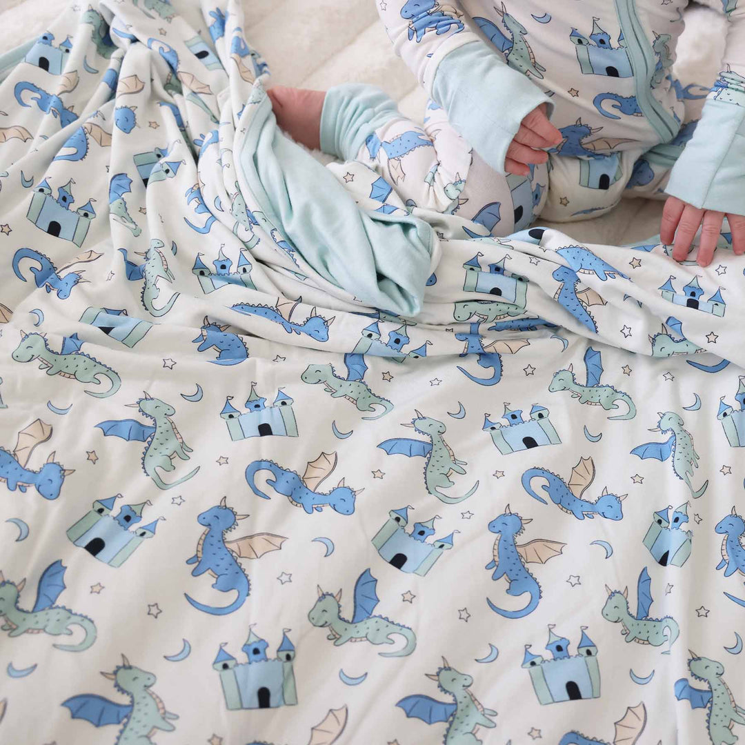Toddler in dragon pajamas with matching dragon and castle blanket 