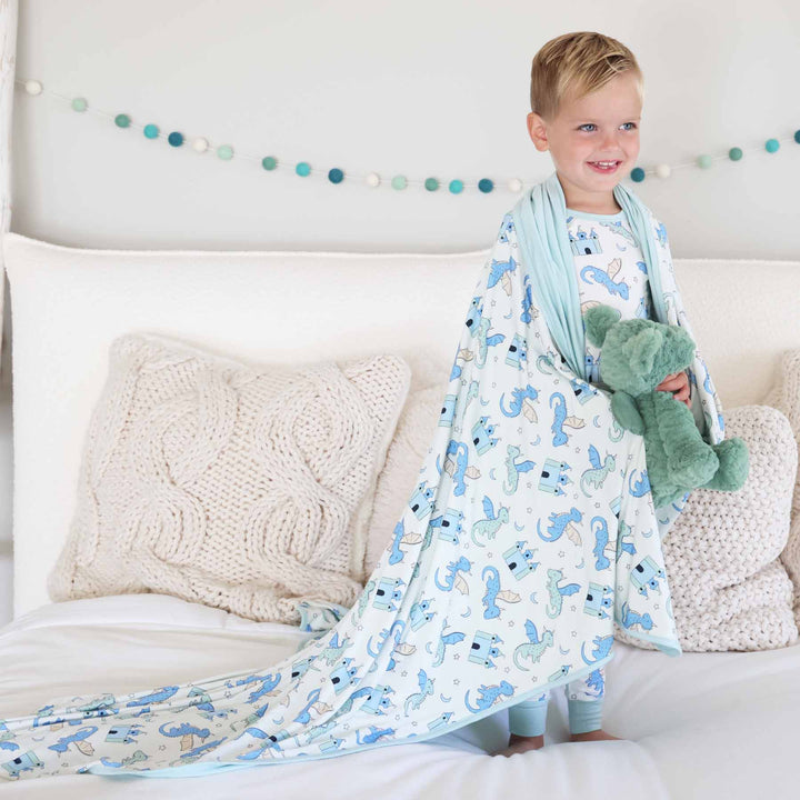 Boy draped in dragon and castle bamboo blanket with coordinating pajamas